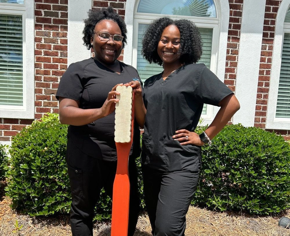 {{ school.name }} students posing with life size toothbrush outside of the facility